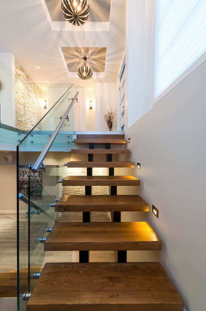 Floating open-riser staircase with glass railing and feature lighting — W Design Group project