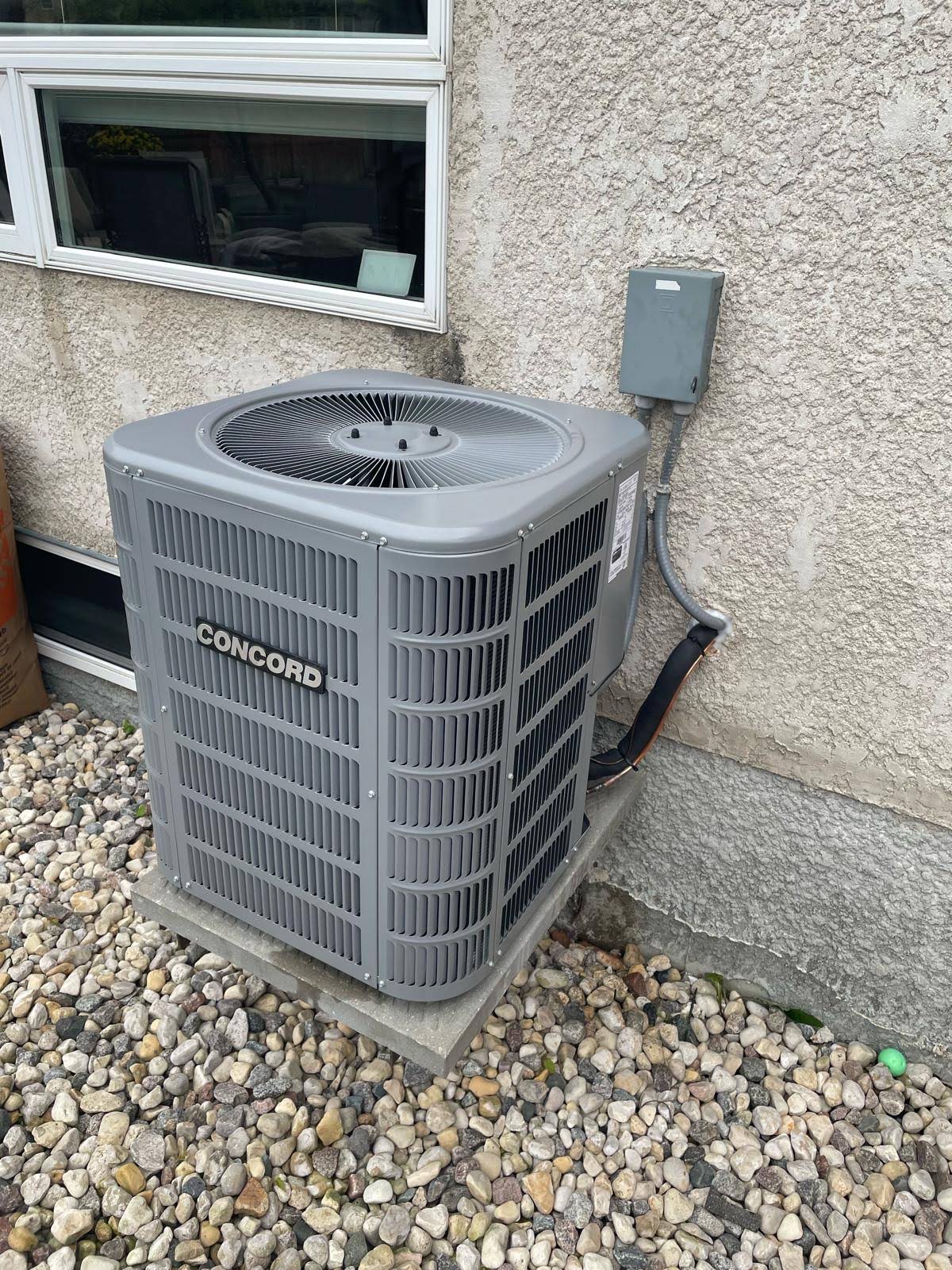 Newly installed Concord central air conditioning condenser on a level pad beside a stucco home exterior with disconnect box and line set