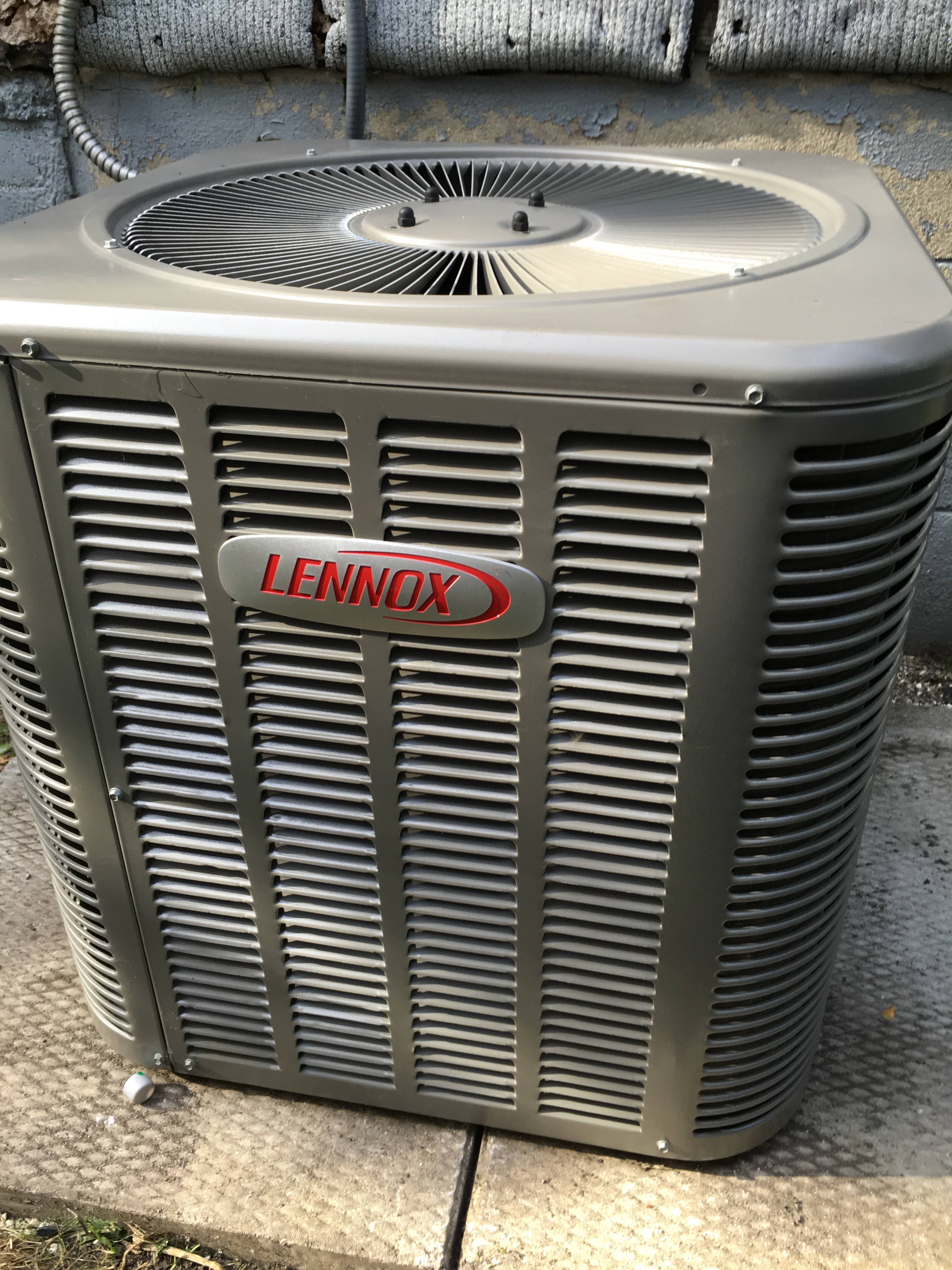 Newly installed Lennox central air conditioner condenser set on a concrete pad against a home foundation