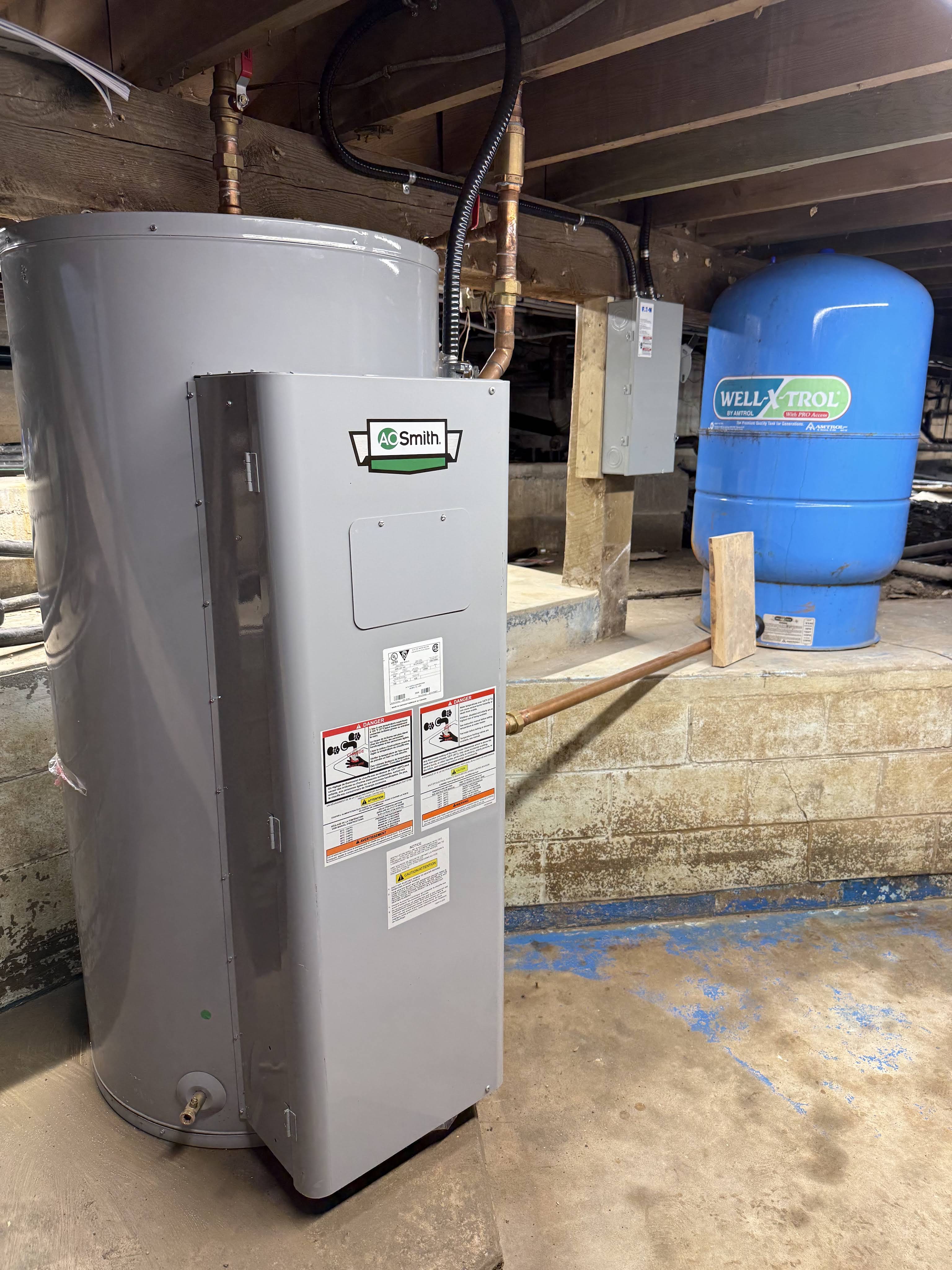 New A.O. Smith commercial water heater installed in a basement beside a Well-X-Trol expansion tank