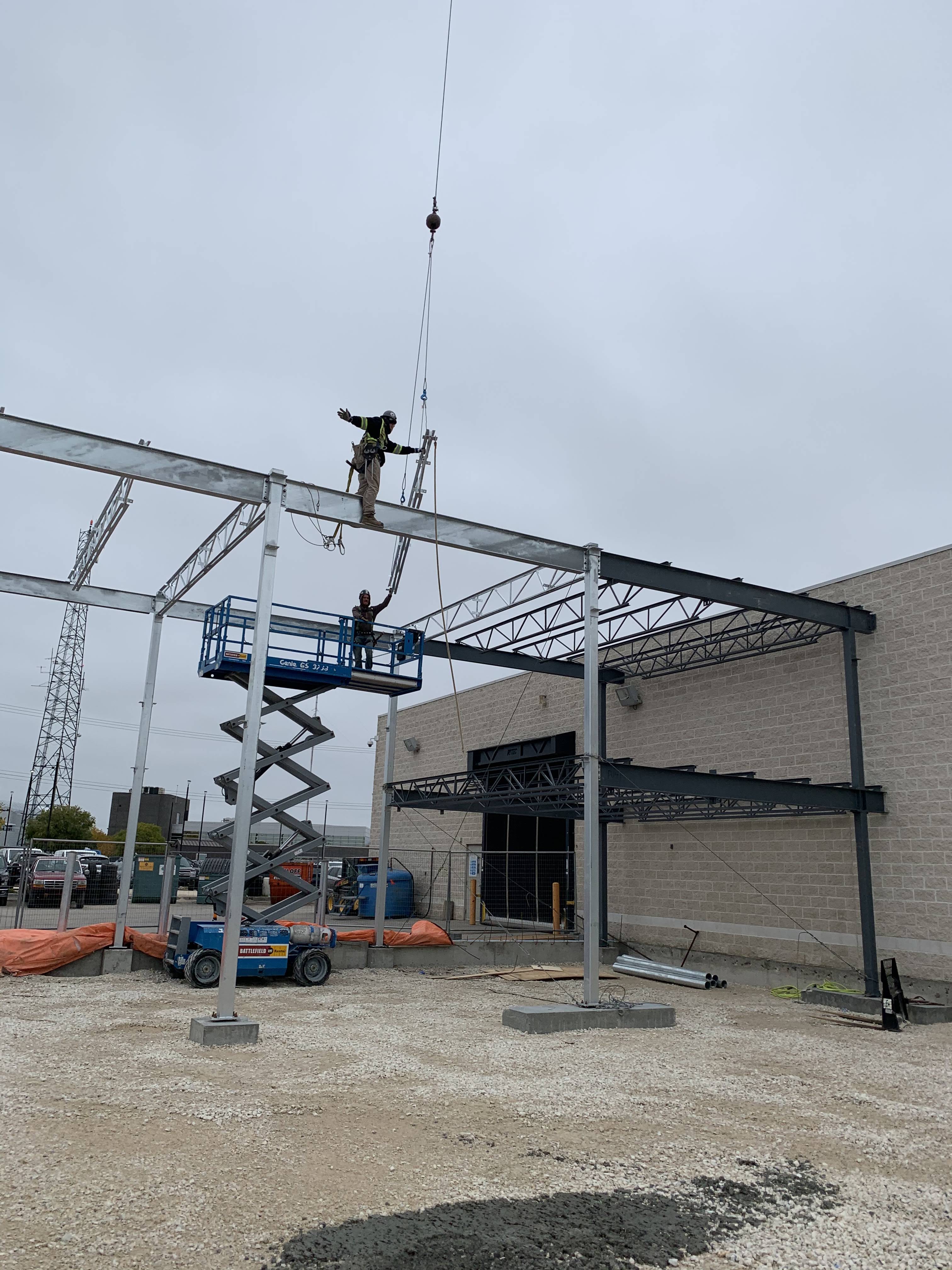 Ironworker landing a beam onto a new storefront frame, Logic Industries