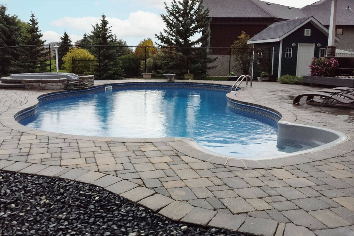This wide angle photograph showcases a complete backyard transformation featuring a beautiful Doral custom freeform pool