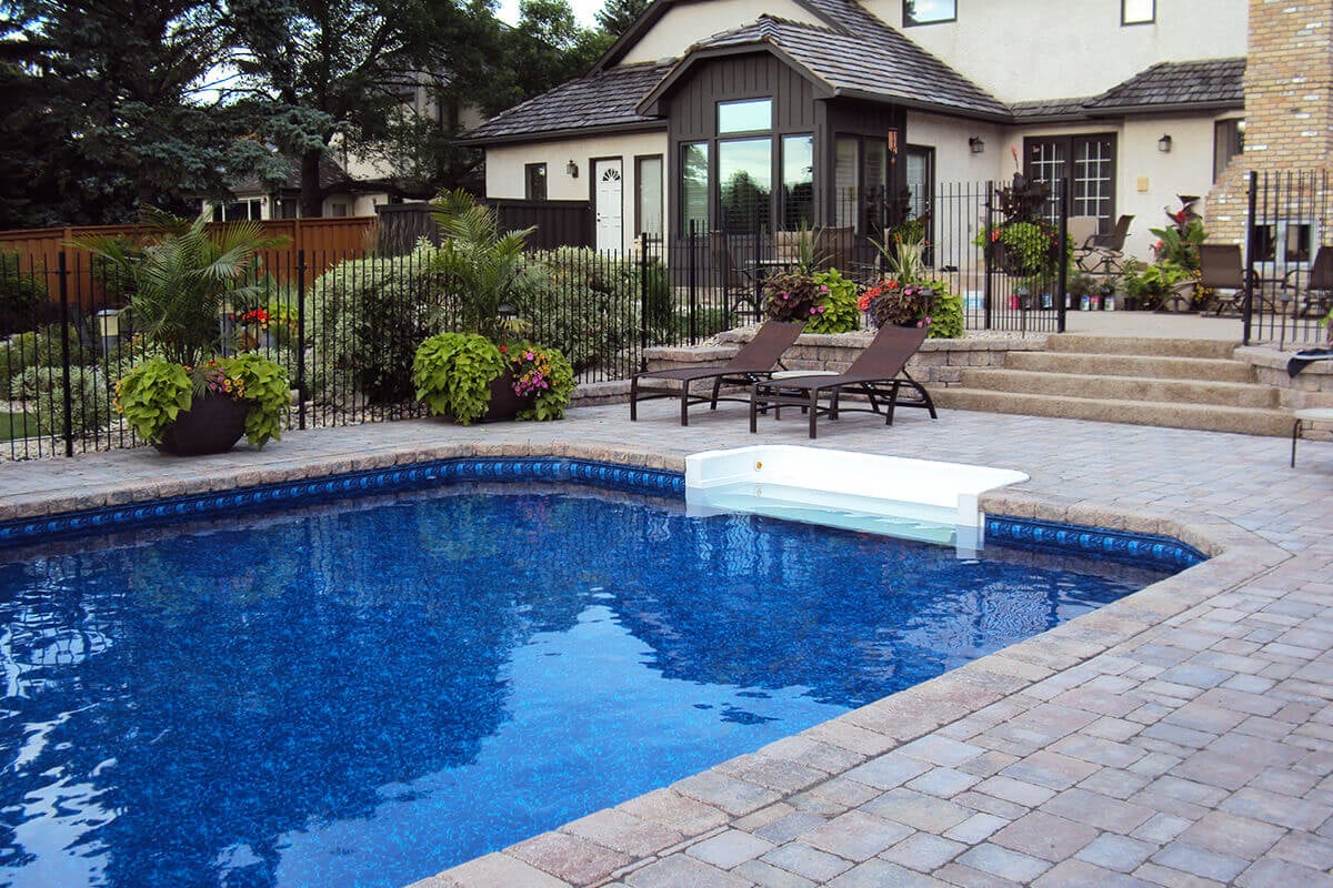 This angled outdoor photograph highlights the relaxing lounging area beside the Shorecrest inground pool with paving sto