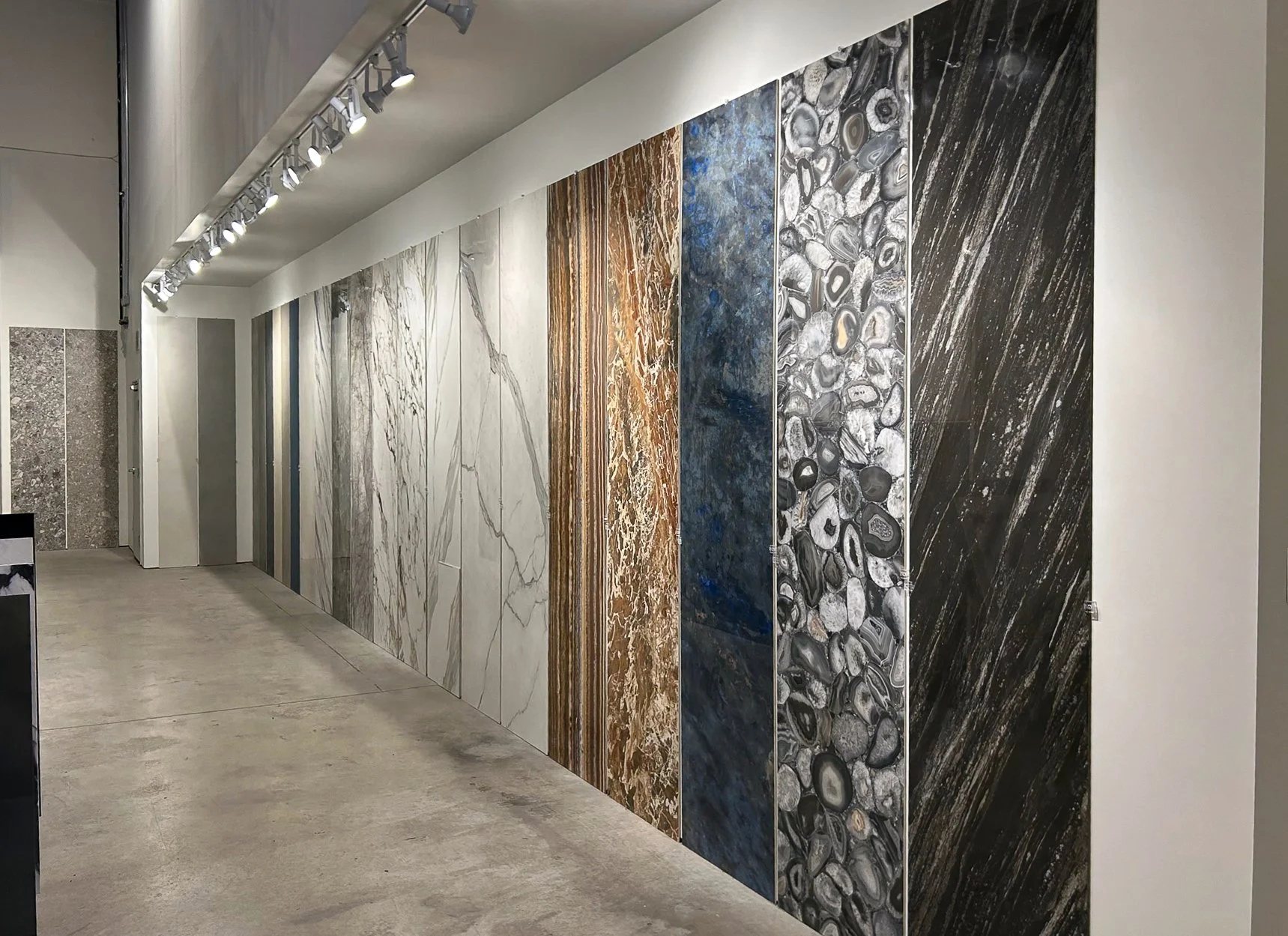 Display of large marble and stone slabs in a showroom, showcasing various patterns and colors.